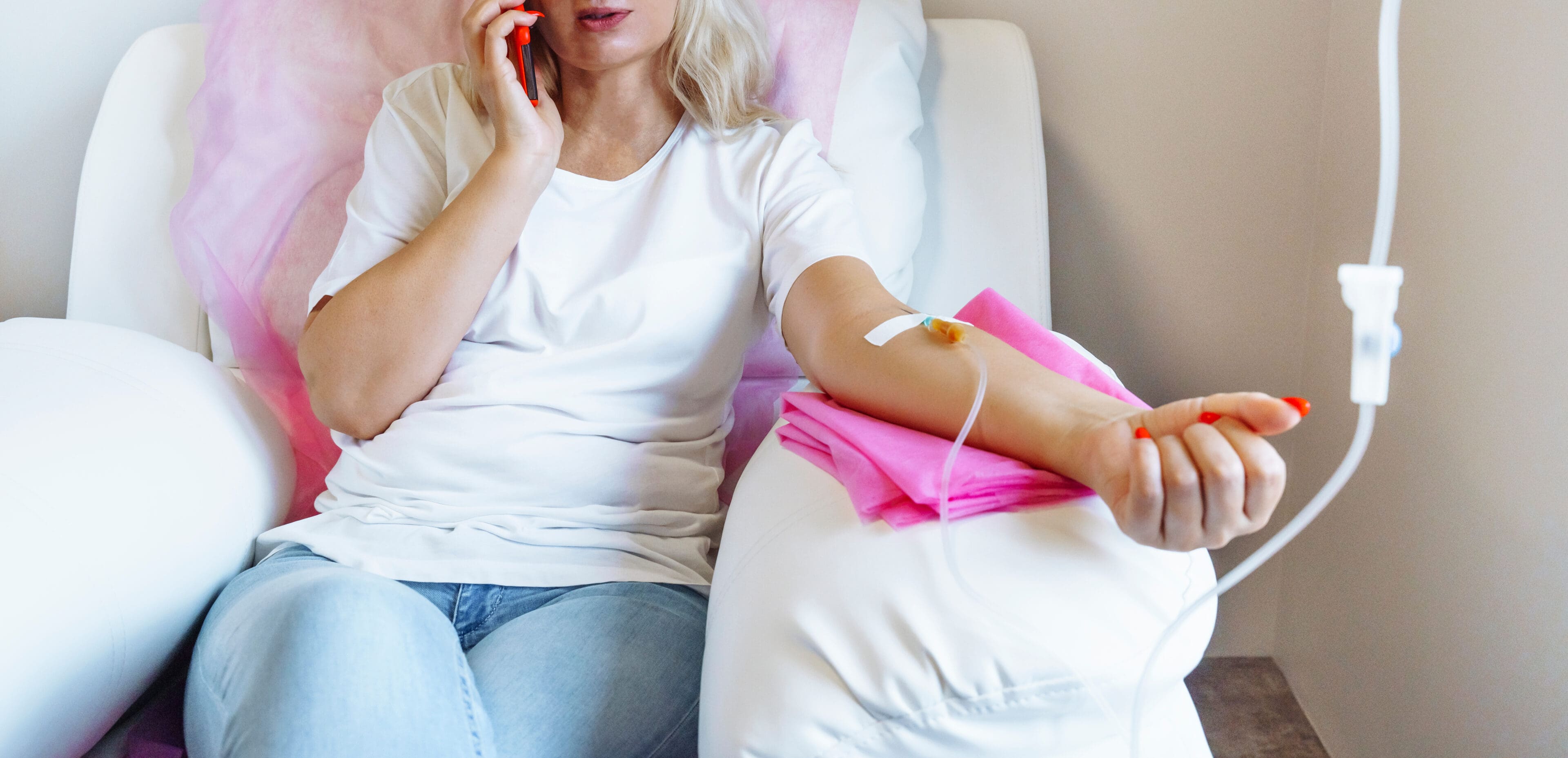 Woman in hospital talking at mobile phone while needle is in arm, Vitamin Therapy Iv Drip Infusion In Women Blood. High quality photo